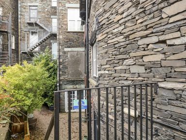 An outdoor area with stone walls metal staircase trees and a metal railing at Dixon Court in Ambleside