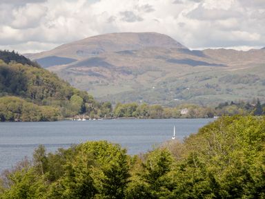 A lake with sailboats surrounded by trees and hills with mountains in the background at Dixon Court in Ambleside