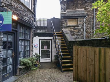 An outdoor courtyard with stone buildings a staircase and plants at Dixon Court in Ambleside