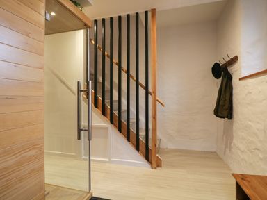 An entryway with wooden stairs and a glass door a coat and hat on hooks on the wall at Dixon Court in Ambleside