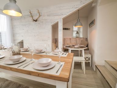 A dining room with two tables set with plates glasses and cutlery and a wall with mounted antlers at Dixon Court in Ambleside
