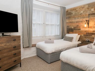 A bedroom with two single beds a wooden dresser and a window with curtains at Dixon Court in Ambleside