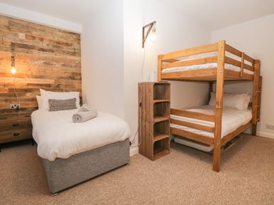 A bedroom with a single bed and wooden bunk beds at Dixon Court in Ambleside