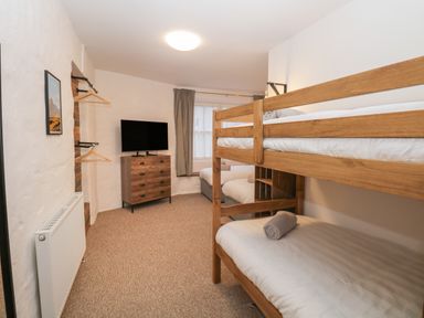 A bedroom with bunk beds a chest of drawers and a TV at Dixon Court Ambleside