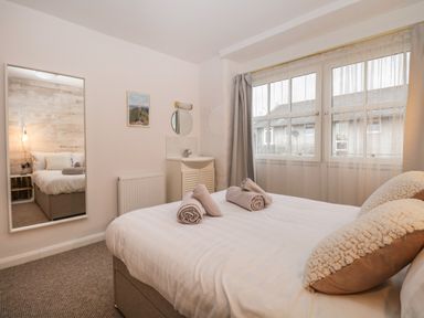 A bedroom with a bed and rolled towels by a window with curtains at Dixon Court in Ambleside