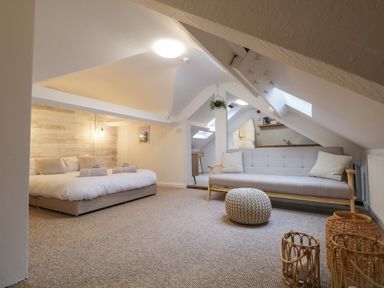 A room with a bed a sofa a knitted pouf and wicker lanterns at Dixon Court in Ambleside