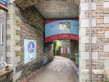 A narrow stone passageway with signs and a red and blue archway reading 101 Lake Road at Dixon Court in Ambleside
