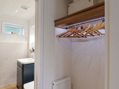 A closet with wooden hangers and a bathroom with a sink and window at Hideaway Lodge in Runswick Bay