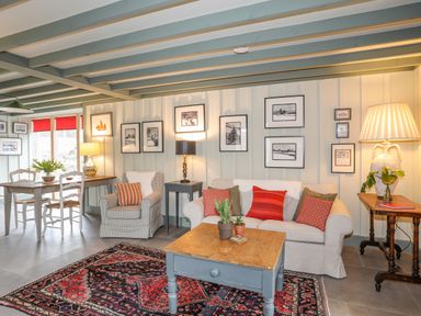 A living room with a sofa armchair wooden coffee table and dining table with chairs at Hen Beudy in Porthmadog
