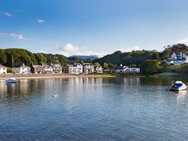 A waterfront village with houses along the shore and boats on the water at Hen Beudy in Porthmadog