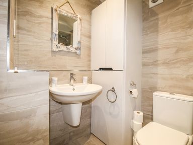 A bathroom with a sink a mirror a cabinet and a toilet at Sunrise Apartment in Weymouth