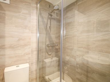 A shower area with a glass door and a toilet in a bathroom at Sunrise Apartment in Weymouth