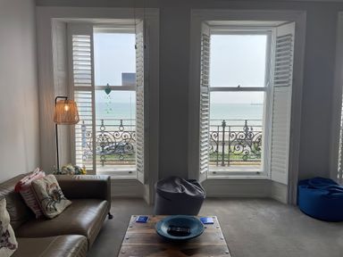 A living room with a sofa and a view of the sea at Sunrise Apartment in Weymouth