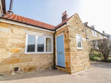 Exterior of a stone house with a blue door and white windows and a tiled roof at Rose Cottage in Faceby near Swainby