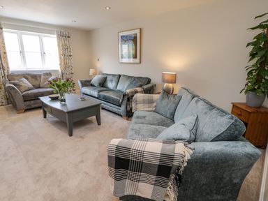 A living room with blue sofas a coffee table with flowers and a window at Rose Cottage in Faceby near Swainby