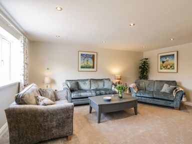 A living room with three sofas a coffee table with flowers two framed pictures on the wall and lamps at Rose Cottage in Faceby near Swainby