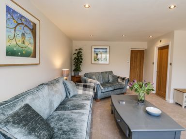 A living room with two sofas a coffee table flowers and framed pictures at Rose Cottage Faceby near Swainby