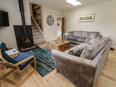 A living room with two gray sofas a wood burning stove and a wooden coffee table at Rose Cottage Faceby near Swainby