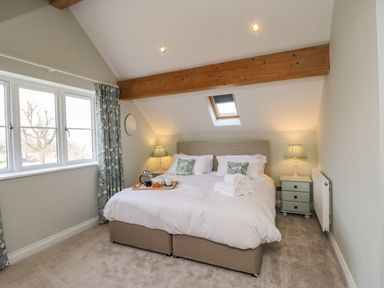 A bedroom with a double bed bedside tables lamps and a small skylight window at Rose Cottage in Faceby near Swainby