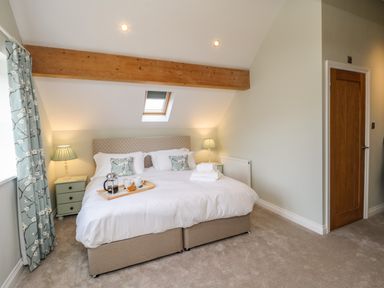 A bedroom with a double bed two bedside tables lamps and a wooden door at Rose Cottage Faceby near Swainby