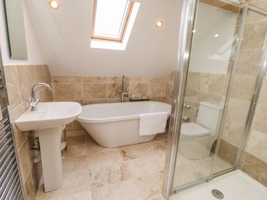 A bathroom with a bathtub sink toilet and glass shower enclosure at Rose Cottage Faceby near Swainby