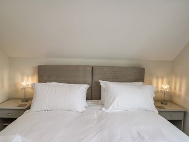 A bed with white pillows and a headboard with two bedside tables and lamps at Rose Cottage in Faceby near Swainby