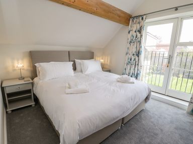 A bedroom with a double bed two bedside tables lamps and glass doors opening to a garden at Rose Cottage Faceby near Swainby