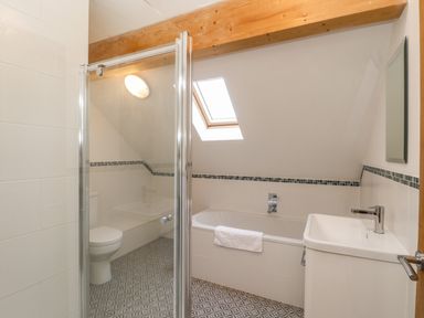 A bathroom with a bathtub a sink a toilet and a glass shower enclosure at Rose Cottage in Faceby near Swainby