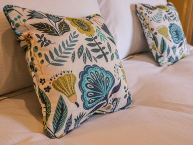 Two floral patterned cushions on a white bed at Rose Cottage Faceby near Swainby