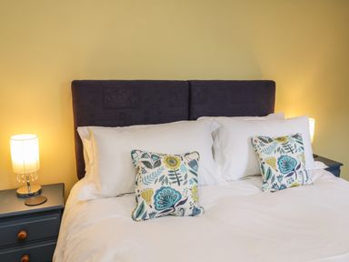 A bedroom with a bed and two bedside tables with lamps at Rose Cottage Faceby near Swainby