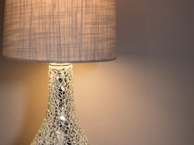 A lamp with a mosaic glass base and a textured fabric lampshade against a plain wall at Rose Cottage in Faceby near Swainby