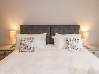 A bedroom with a double bed white bedding floral pillows two bedside tables and lamps at Rose Cottage Faceby near Swainby