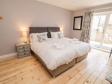 A bedroom with a double bed lamp bedside table and glass doors at Rose Cottage Faceby near Swainby
