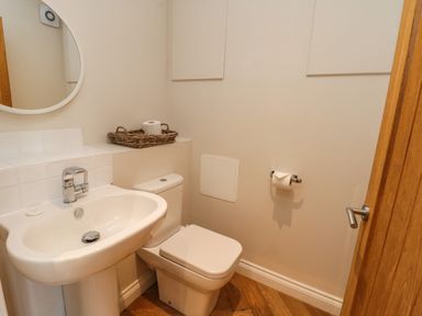A bathroom with a white sink and toilet roll basket next to toilet at Rose Cottage in Faceby near Swainby