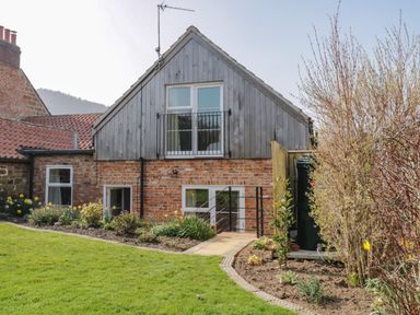 Exterior view of a brick and wood house with garden and pathway at Rose Cottage in Faceby near Swainby