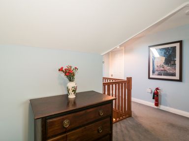 A hallway with a wooden chest of drawers with a vase of flowers and a framed picture on the wall at Morgan House in Middlezoy