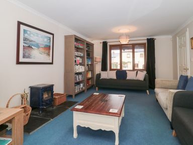 A living room with sofas a wooden coffee table a bookshelf wood stove and a framed picture at Morgan House in Middlezoy