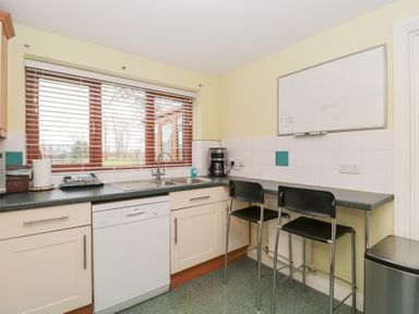 A kitchen with a dishwasher sink coffee maker and two black chairs at Morgan House in Middlezoy