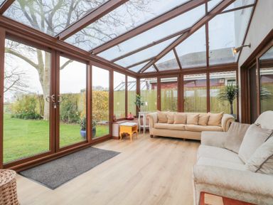 A conservatory with two sofas a small table with plants and garden view at Morgan House in Middlezoy