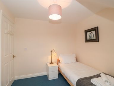 A small bedroom with a single bed a bedside table with a lamp folded towels on the bed and a framed picture on the wall at Morgan House in Middlezoy