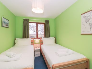A bedroom with two single beds a window with curtains and a lamp on a nightstand at Morgan House in Middlezoy