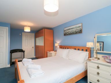 A bedroom with a wooden bed white bedding bedside tables lamps wardrobe and a floral painting at Morgan House in Middlezoy