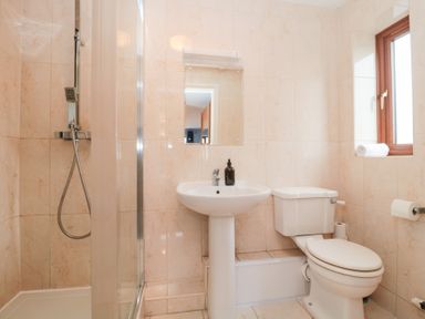 A bathroom with a shower, a pedestal sink with soap dispenser, a toilet, and a window with a towel on the sill at Morgan House in Middlezoy