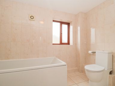 A bathroom with a bathtub a toilet and a window at Morgan House in Middlezoy