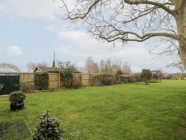 A garden with grass lawn trees fencing a trampoline and clothes drying rack at Morgan House in Middlezoy