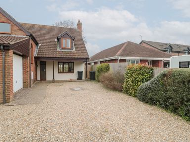 A driveway with gravel and bushes leading to a house with a tiled roof and windows at Morgan House in Middlezoy