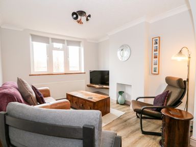 A living room with a sofa armchair coffee table and television at 57 Southend Road in Hunstanton