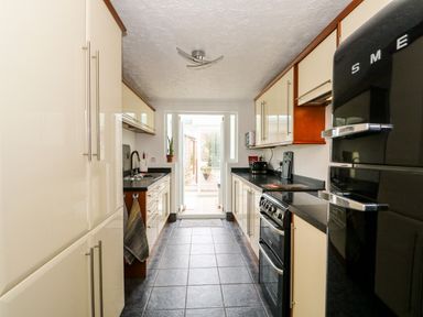 A kitchen with cabinets countertops a stove and a black refrigerator at 57 Southend Road in Hunstanton