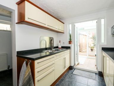 A kitchen with cream cabinets black countertops a double sink and towels hanging on cabinet handles at 57 Southend Road Hunstanton