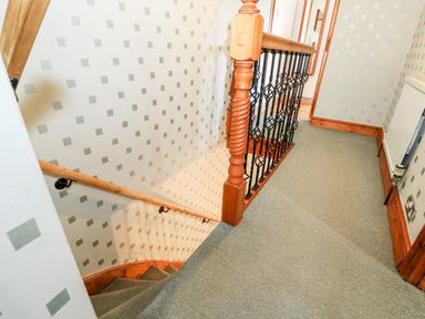 A carpeted staircase and landing area with wooden handrails and spindles at 57 Southend Road Hunstanton